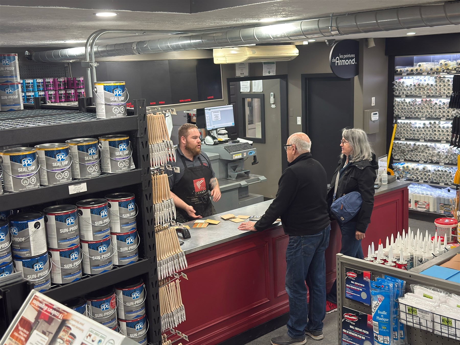 Un membre de notre &eacute;quipe conseille des clients au comptoir du magasin.